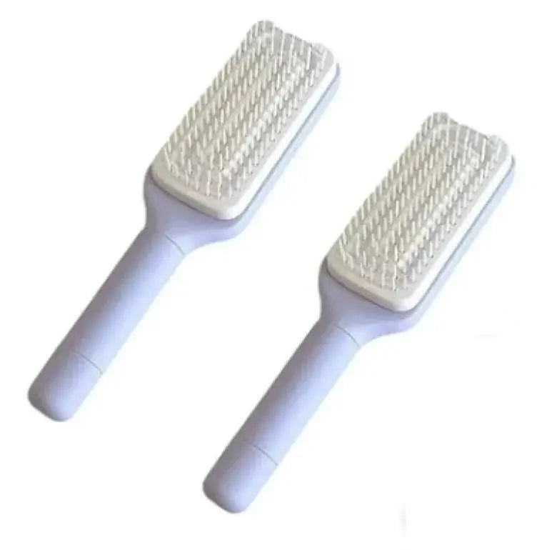 Two hairbrushes with a white and blue color scheme, held in a person's hand, with a round pad and detangling bristles visible.